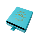 A turquoise blue rectangular product box with a sliding lid, featuring a gold foil 'Fitzzy' logo on the top. The box is shown slightly open, revealing a dark interior, on a clean white background.