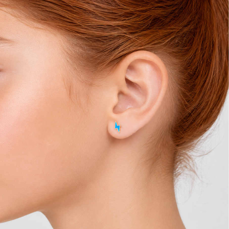 Close-up of a person wearing a small blue lightning bolt earring on a plain background