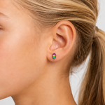 Close-up of a young girl wearing rainbow popsicle stud earrings on a plain background
