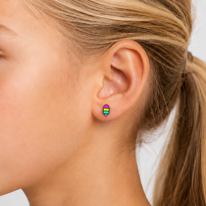Close-up of a young girl wearing rainbow popsicle stud earrings on a plain background