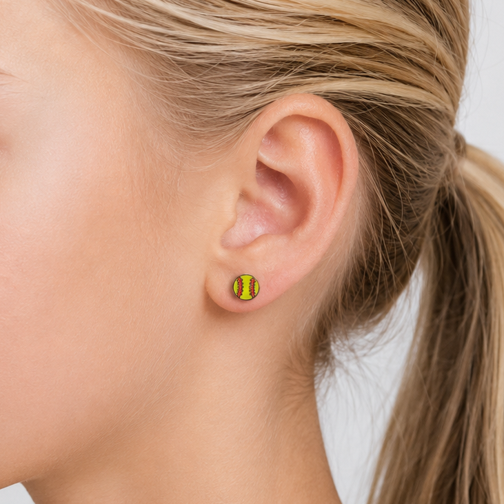 Close-up of a young girl wearing softball gold earrings with a plain background